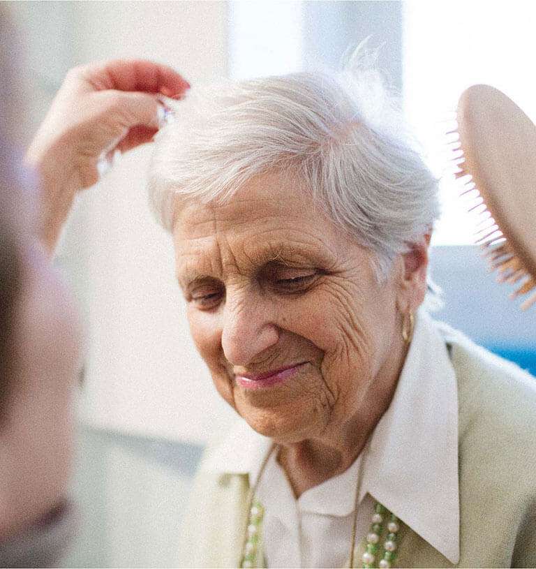 Emma, an elderly care client, tending roses at her local gardening club