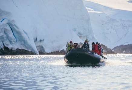 Passengers onboard inflatable Zodiak boat exploring the frozen Antarctic Peninsula.