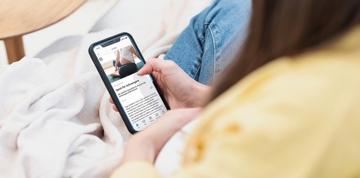 Schwangere Frau scrollt durch den personalisierten Feed der LILLYDOO App auf Smartphone
