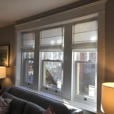 White roman shades across three windows