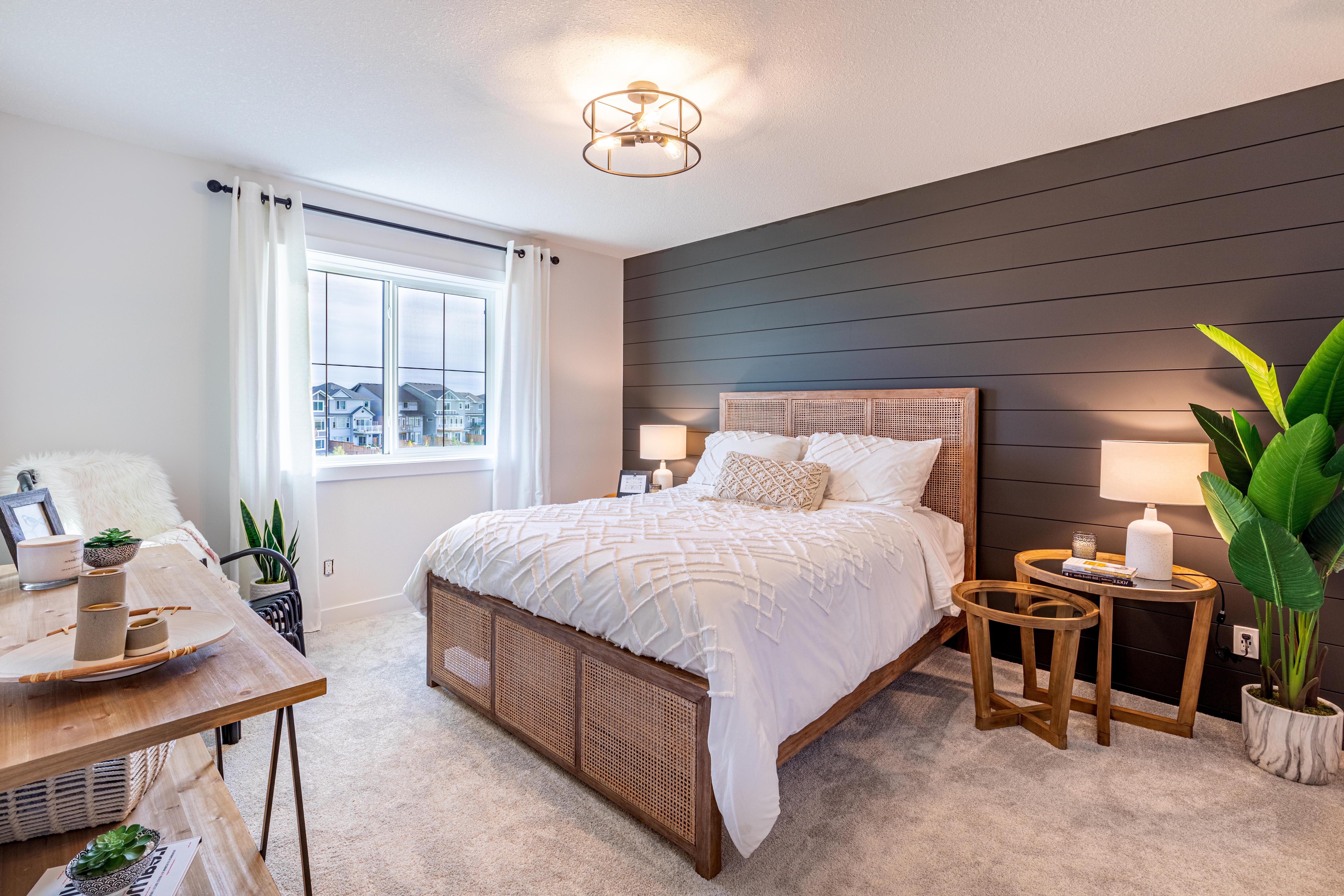 White bedroom with shiplap focal wall, wooden fixtures and bohemian accents