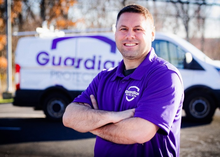Guardian Protection professional installer standing in front of van
