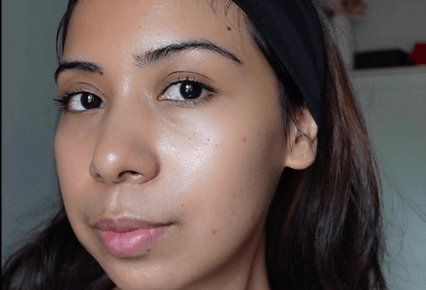 A person with a black headband and clear skin looking at the camera.