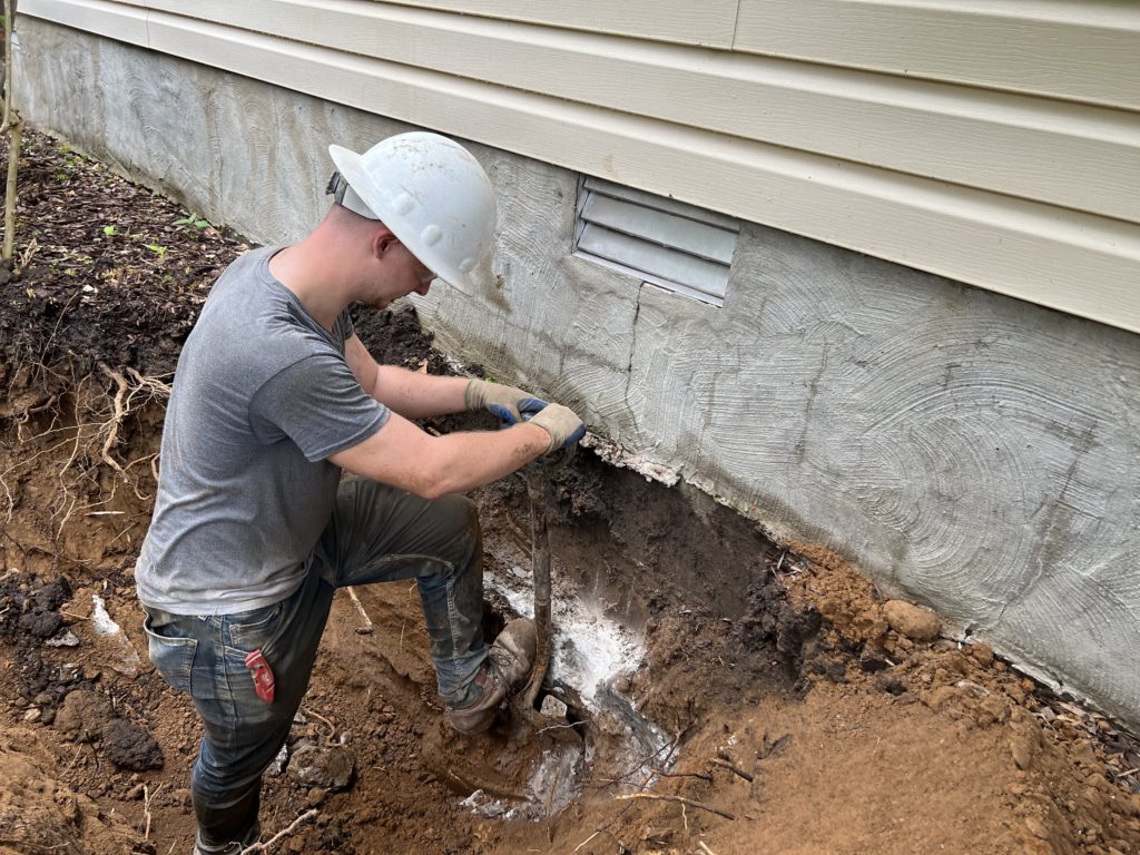A foundation specialist working beside a home foundation