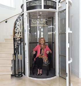 Pneumatic tube elevator with woman in wheelchair inside.