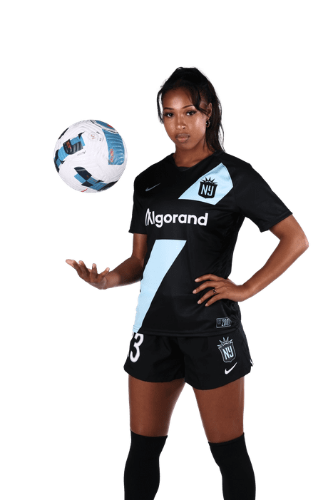 Midge Purce in uniform holding a soccer ball in her hand.