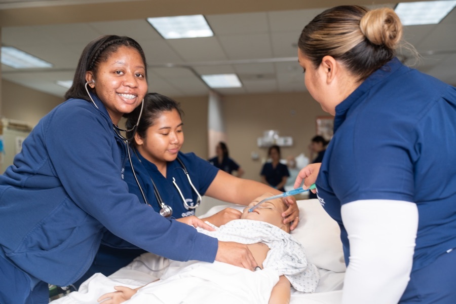 Vocational nursing students practicing patient assessment on a simulation mannequin