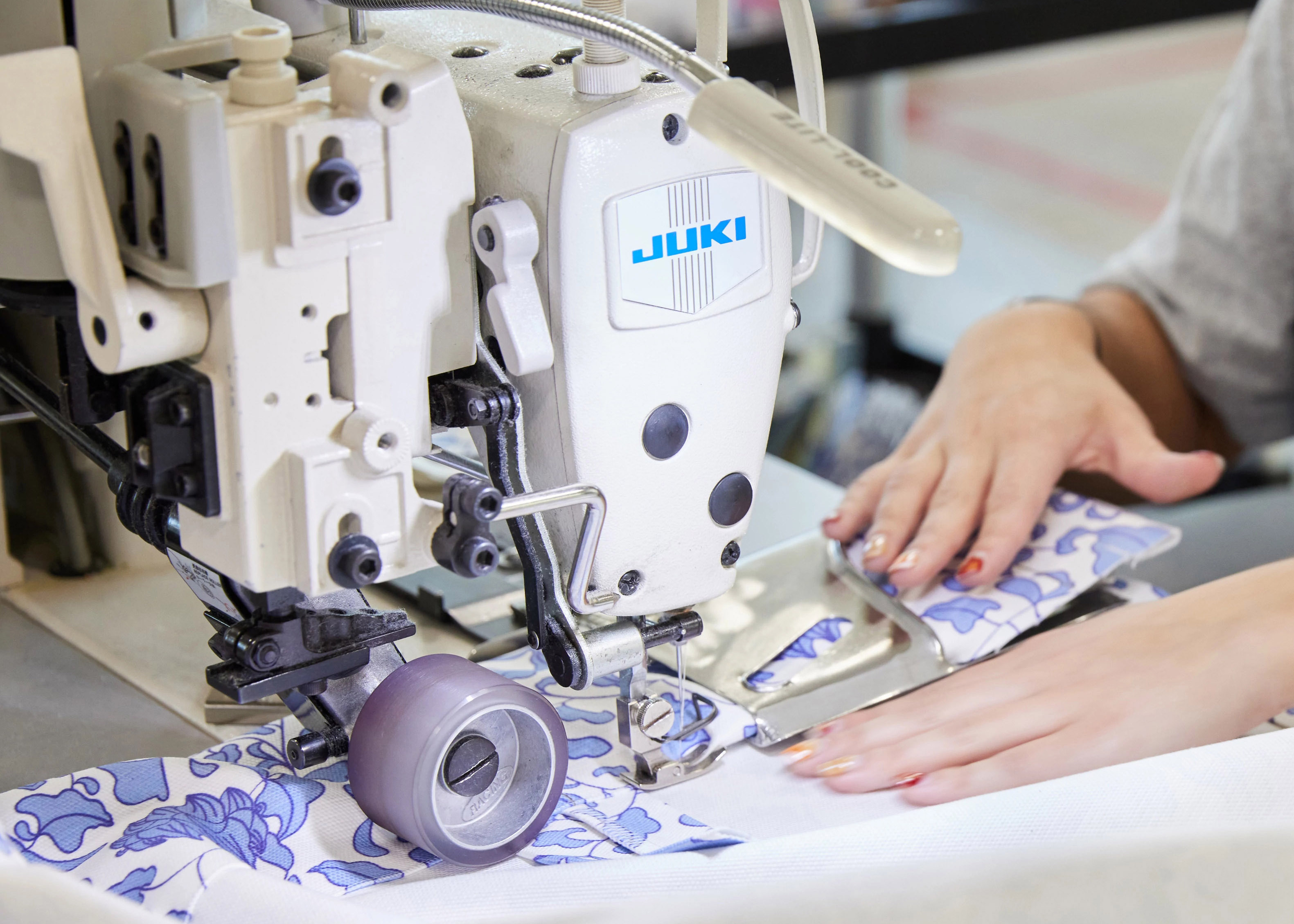 Hands feeding fabric through sewing machine