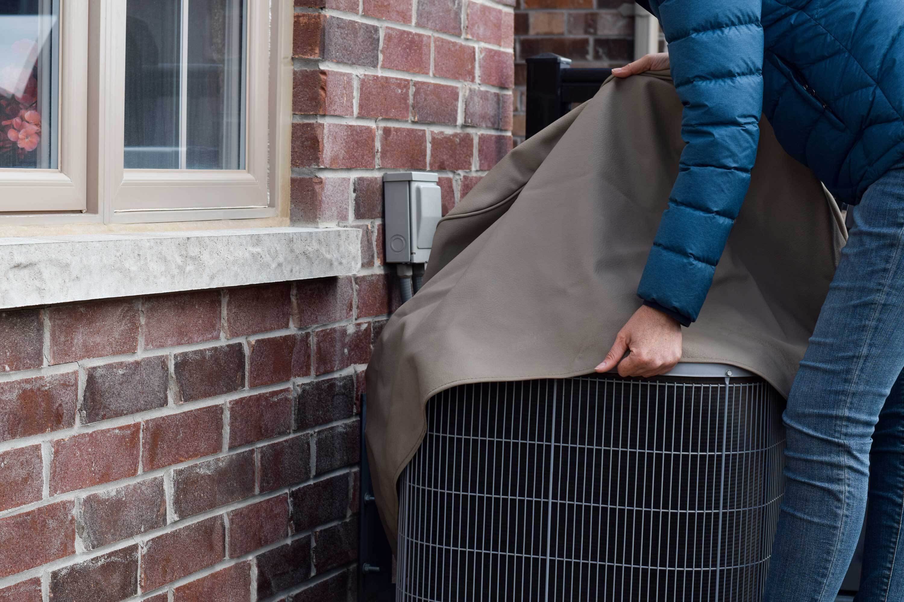 Person winterizing exterior AC unit.