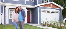 Couple smiling in front of home