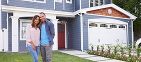 Couple smiling in front of home