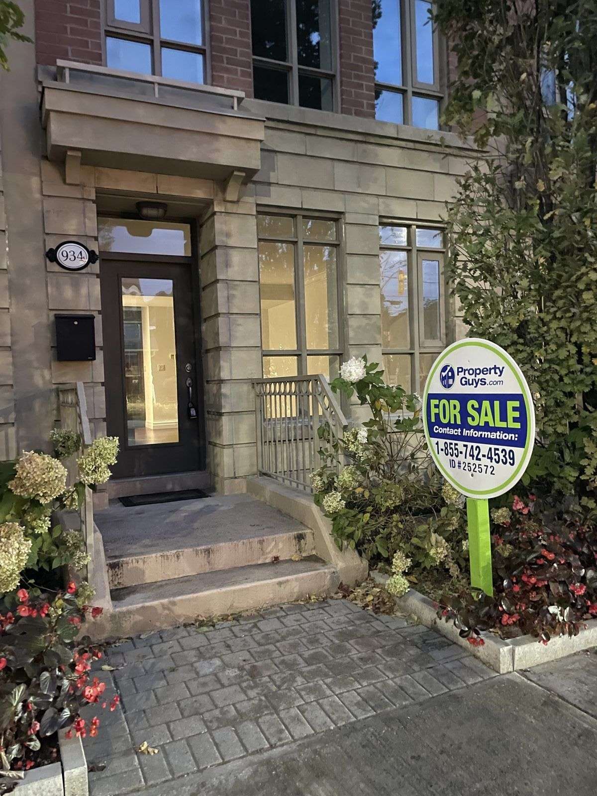 A PropertyGuys.com FOR SALE sign in front of a Toronto townhouse