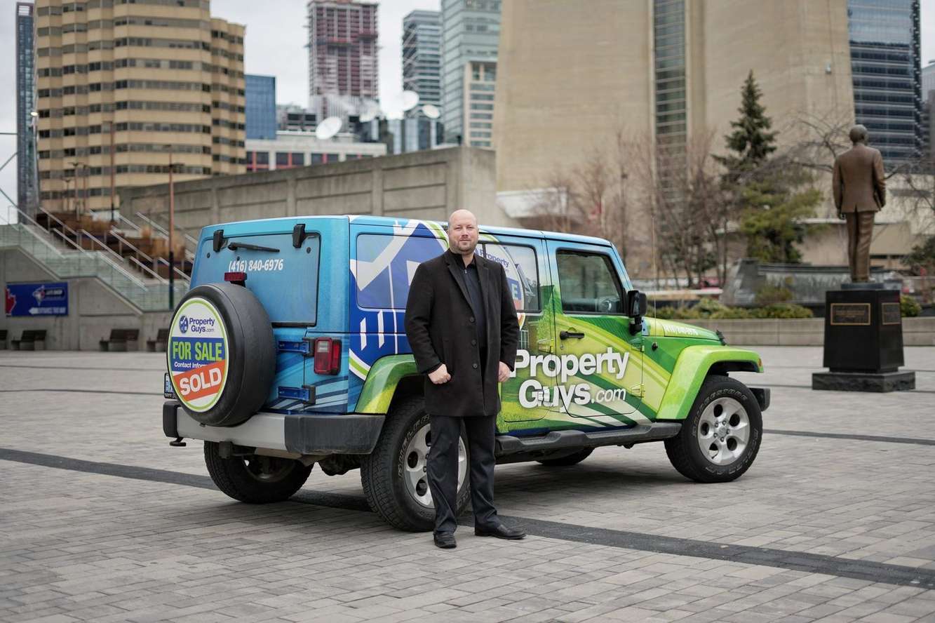 Nathan Dautovich, owner of PropertyGuys.com Toronto, beside the PropertyGuys Jeep in downtown Toronto