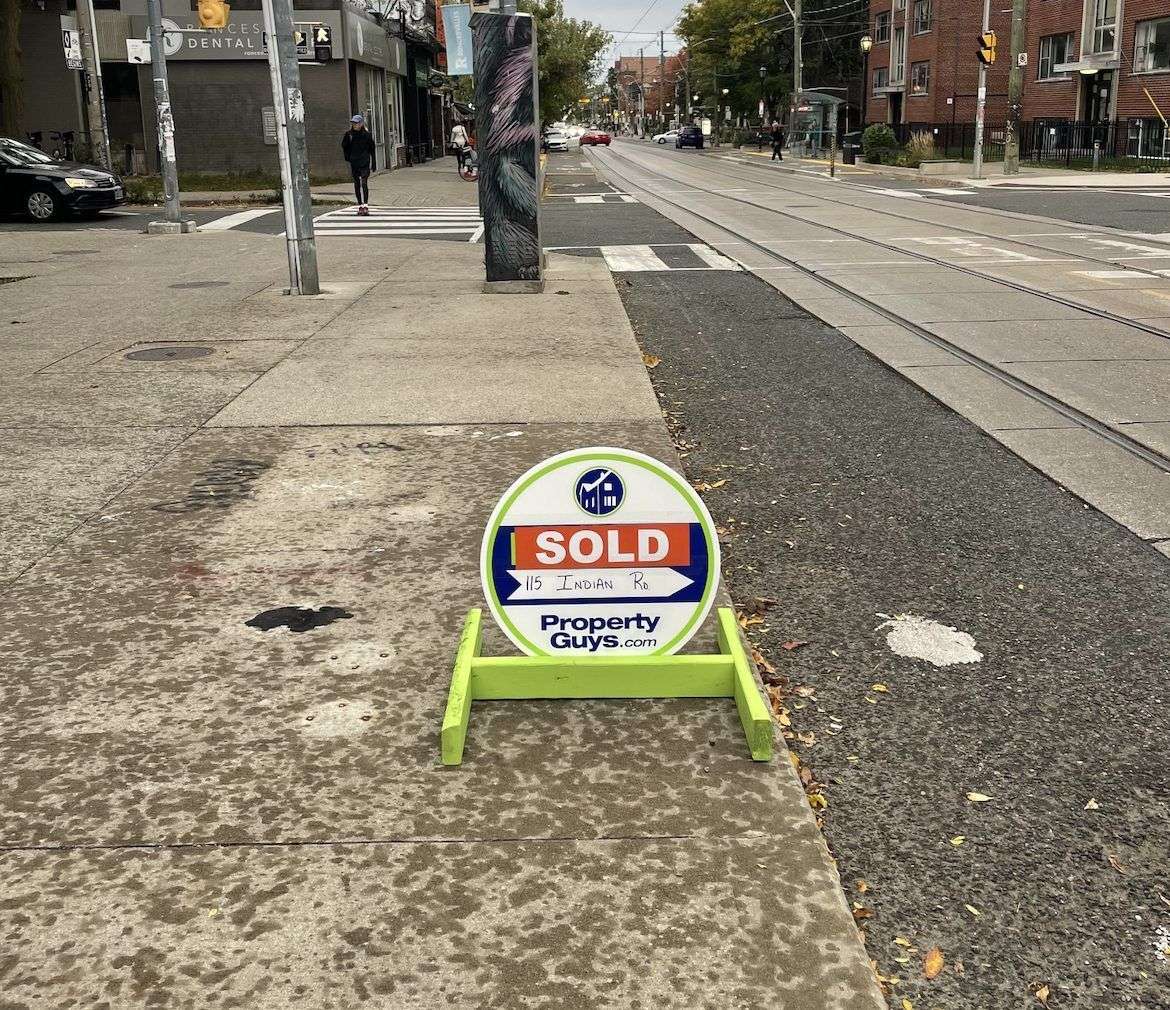 A PropertyGuys.com SOLD sign on a Toronto street corner