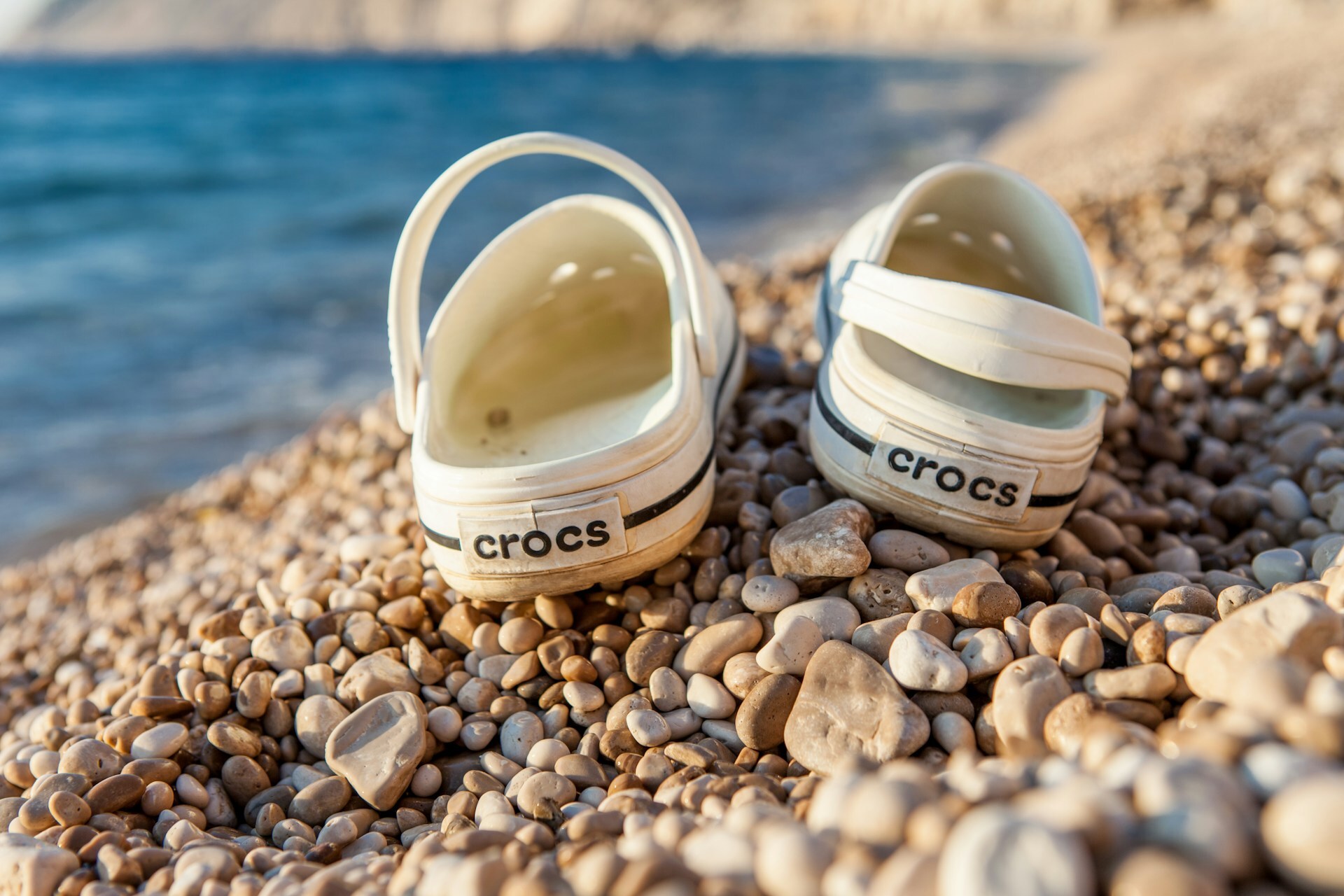 crocs shoes on pebbled beach
