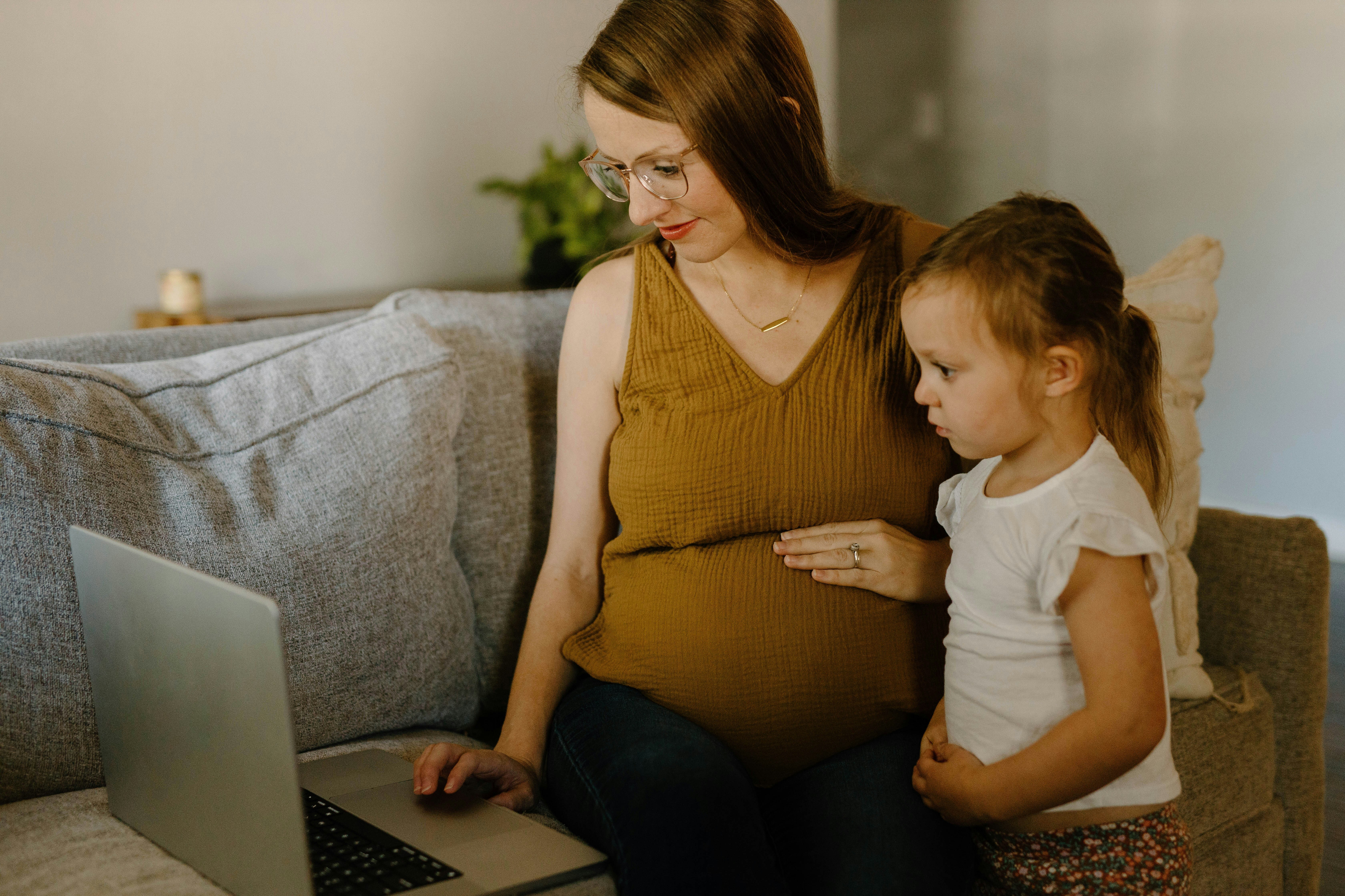 pregnant woman with child looking at laptop