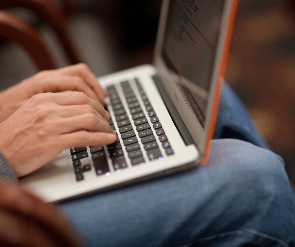 Hands typing on a laptop