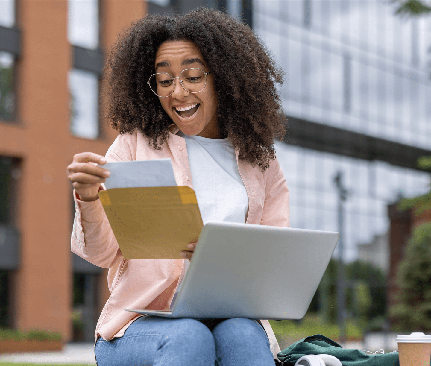 Prospective student opening mail outdoors with a laptop