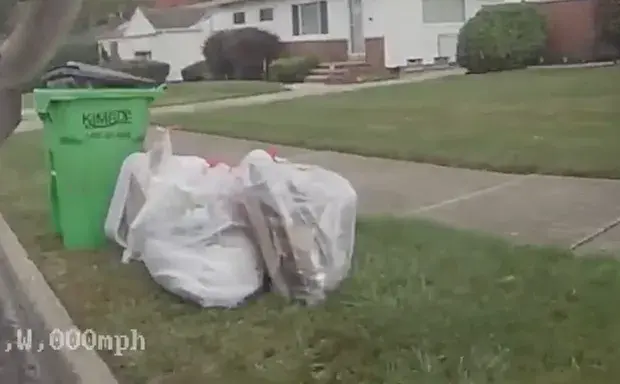 Curb video: extra waste bags beside a green curbside cart