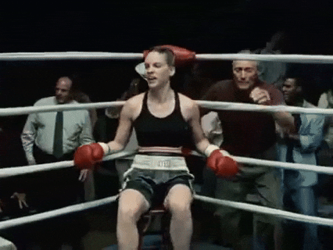 A fighter in her corner between rounds, her trainer leaning in