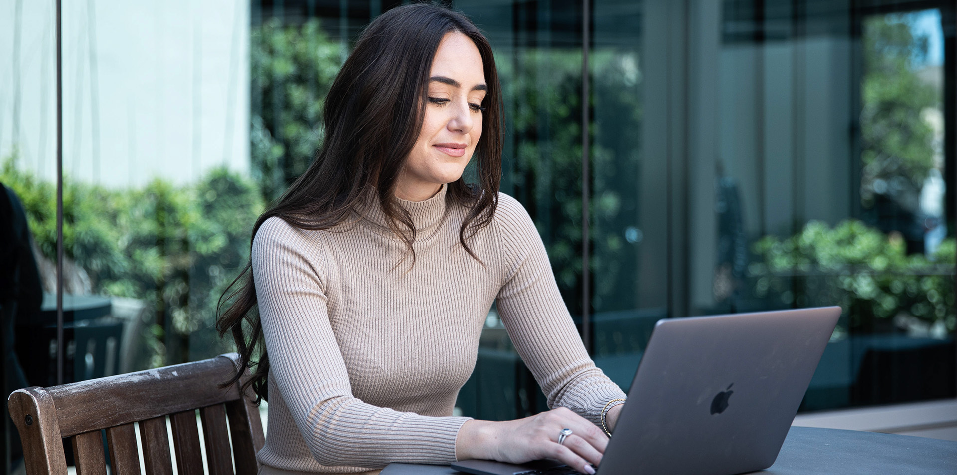 A woman outdoors using her laptop.