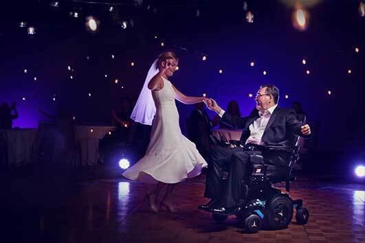 Tom Joiner in a wheelchair dancing with his daughter, Diana, at her wedding reception