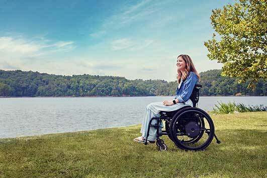 Caroline Hazel in wheelchair at a lake on a sunny day