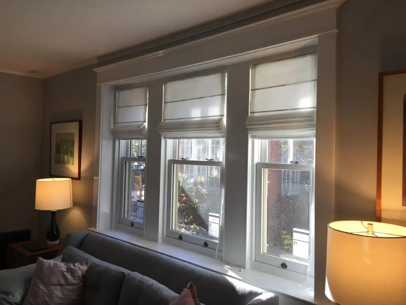 White roman shades across three windows