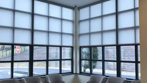 Roller shades across a corner of tall windows