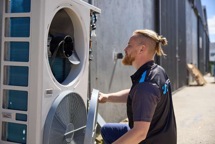 Technician working on an outdoor ducted air conditioning unit