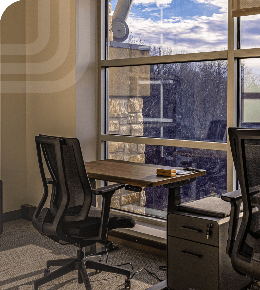 Beautiful office with stunning outside views. Hardwood desks beside each other with large windows.