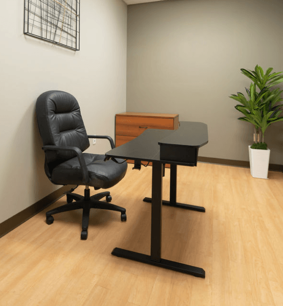 Large training or classroom-style room with rows of mobile desks and chairs, wall-mounted TV, whiteboard, projector, and American flag.