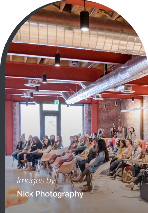 Large crowd seated in event space listening to presenter.