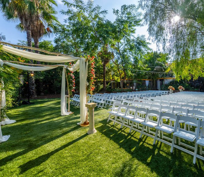Outdoor wedding ceremony setup on a green lawn with white chairs.