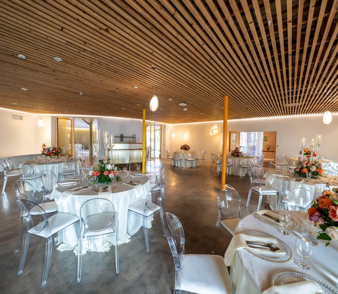 Wedding reception room with a modern wood slat ceiling and concrete floors.