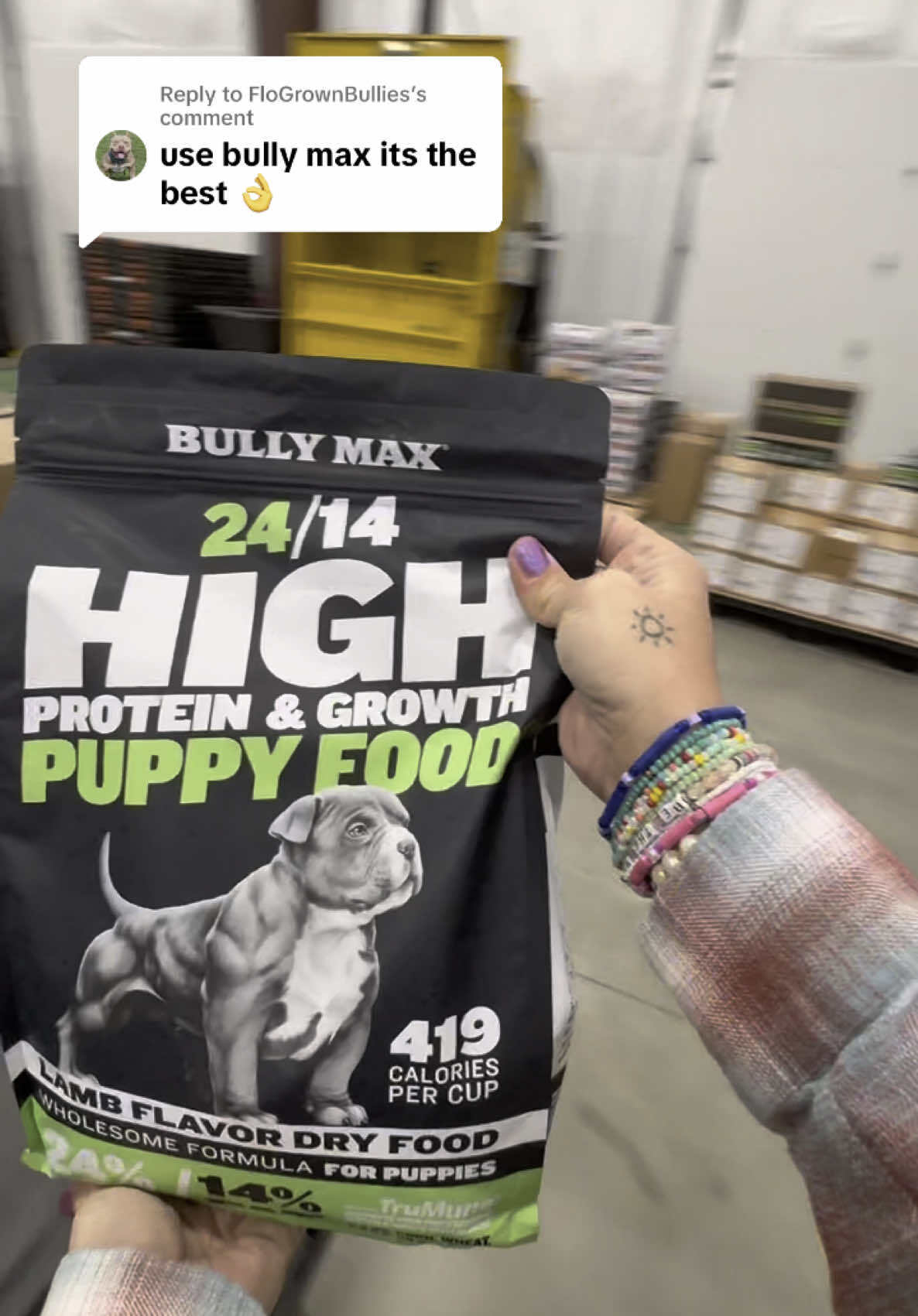 Bag of Bully Max 24/14 High Protein and Growth Puppy Food held up in the Bully Max warehouse, with a customer comment: use Bully Max, it's the best
