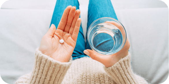 woman holding birth control pill and water
