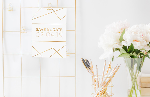 Un esempio di save the date per matrimonio. Un Biglietto Bianco e oro con su scritto data del matrimonio e luogo.