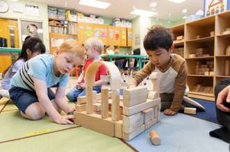 Preschool-age students playing with wooden blocks