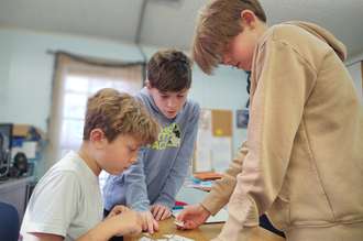 3 boys looking at a science experiment