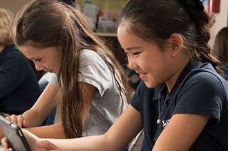 An image of two young, elementary-age girls studying at their desks.