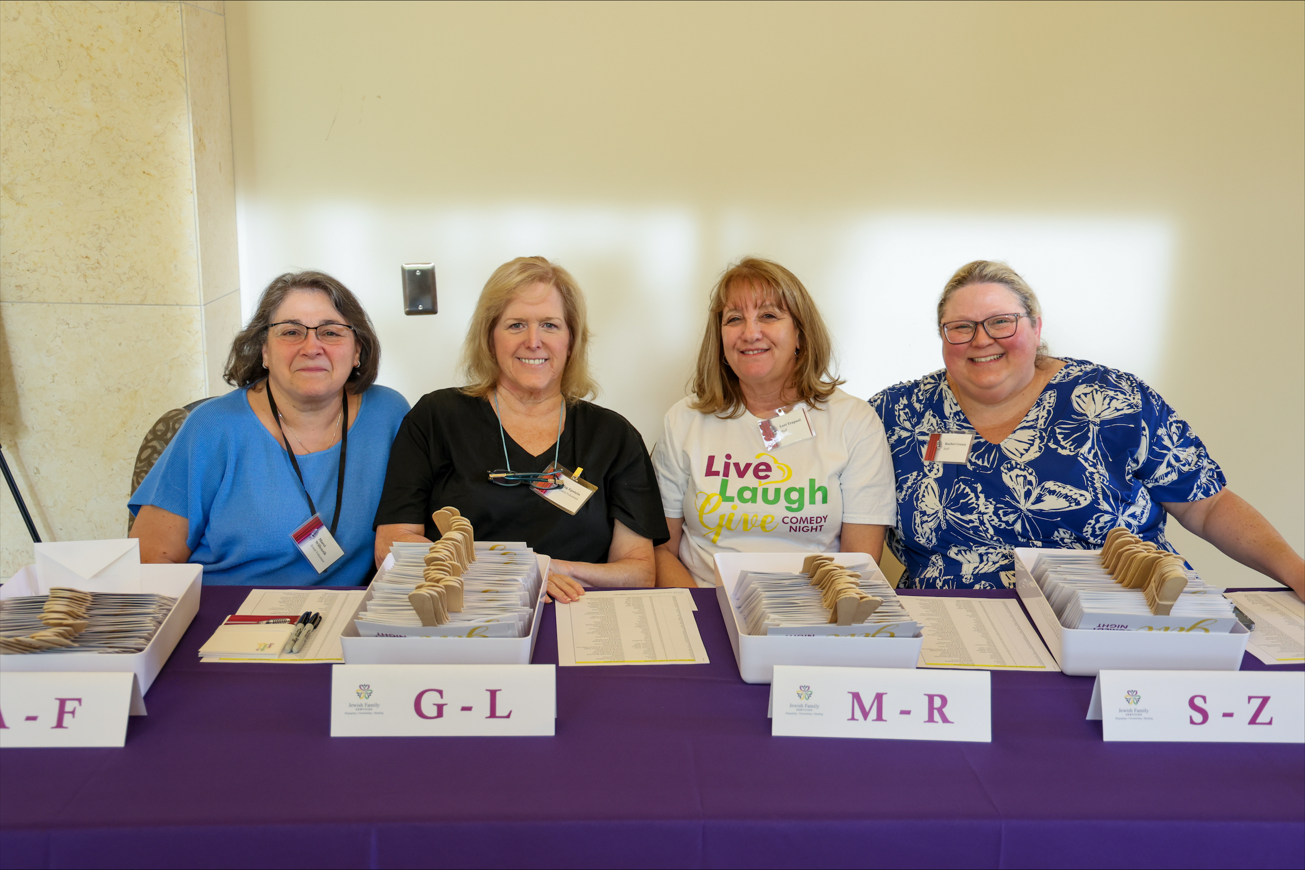 Four Jewish Family Services volunteers seated at an event registration table.