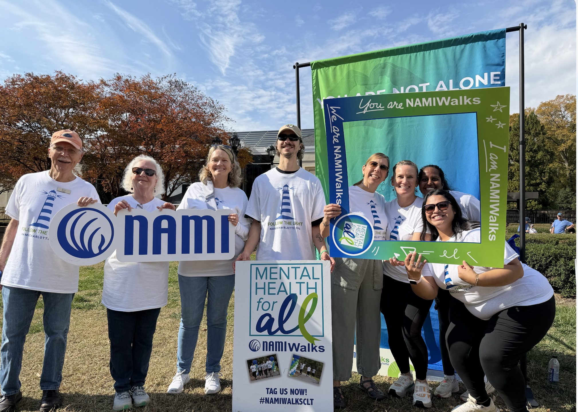 NAMIWalks Charlotte participants posing outdoors with mental health awareness signs and a NAMIWalks photo frame.