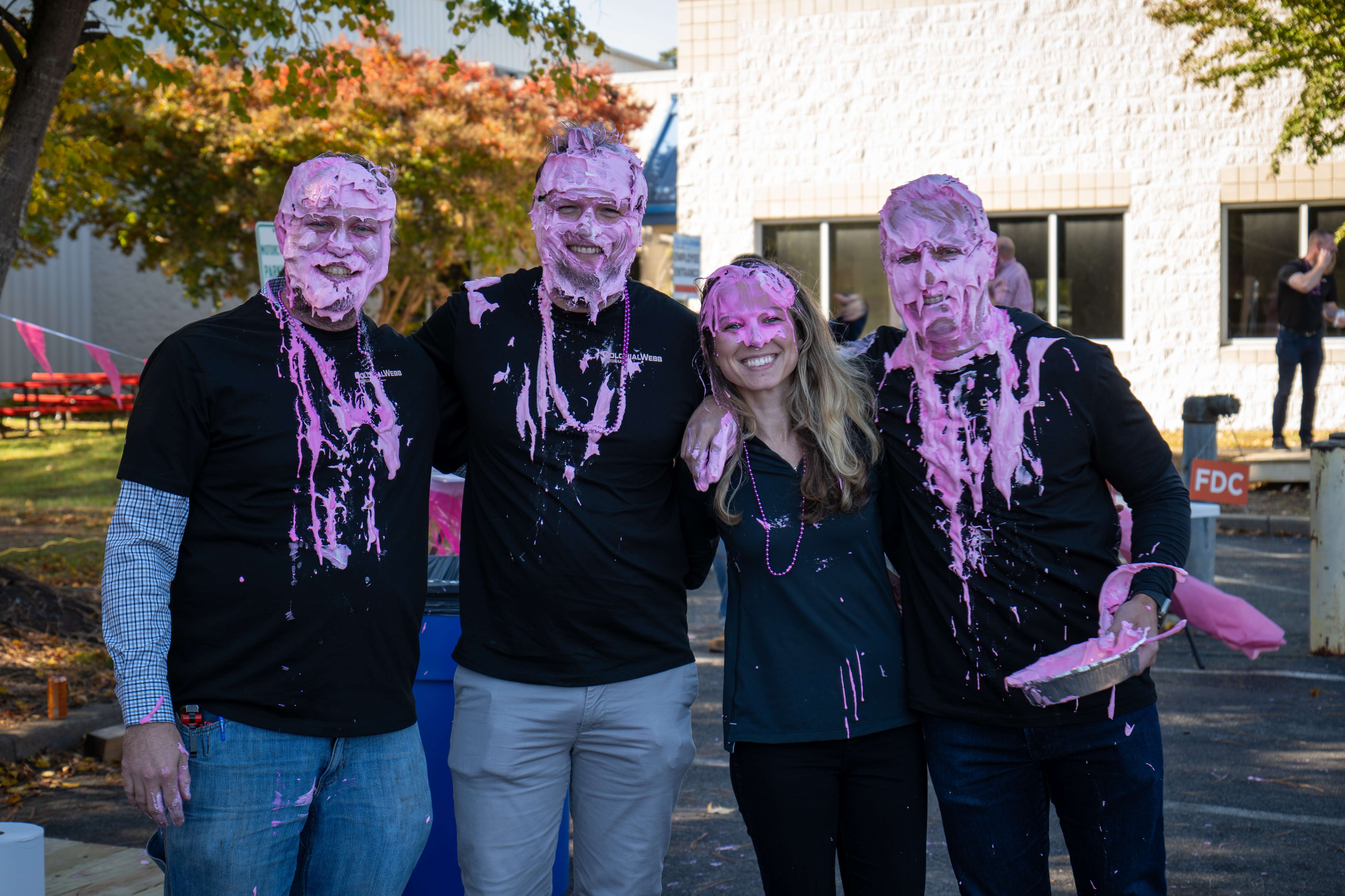 A group of smiling ColonialWebb Pies for a Cure participants covered in pink pie