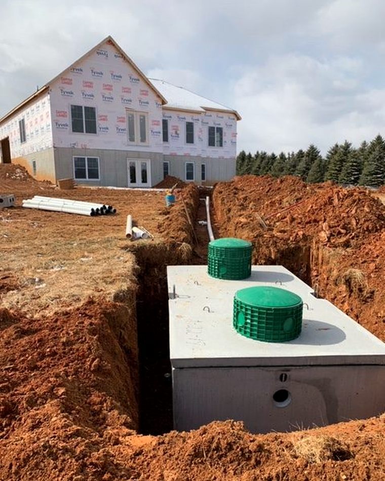 SouthernGent septic tank set in red Alabama clay with a new home build in the background