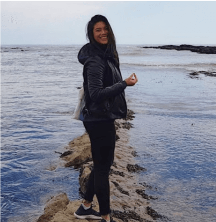 Member smiling at the camera while outside at the beach.