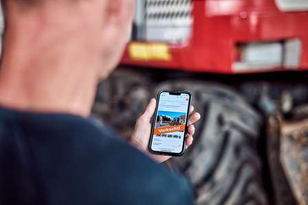 Een afbeelding van een man die een mobile telefoon in handen heeft waarop de melding "verkocht" staat. Dit illustreert een succesvol verkochte kavel.